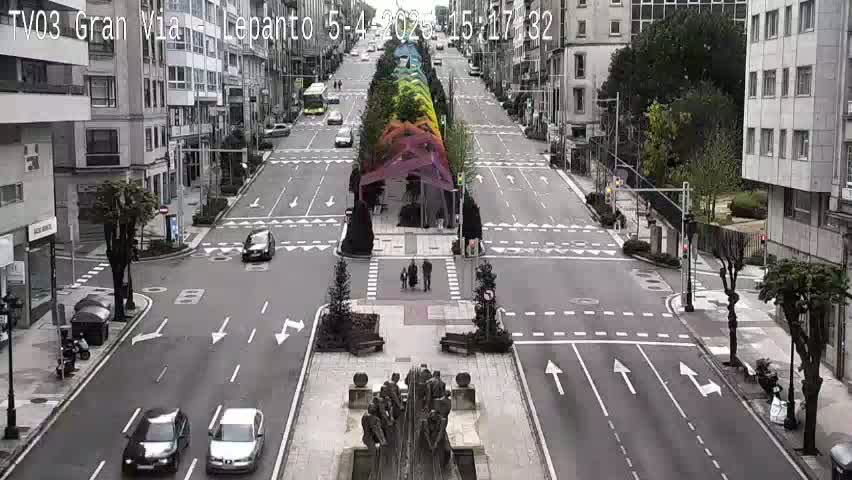 A wide, mostly empty city street with a colorful canopy structure in the center, under a mostly clear sky.