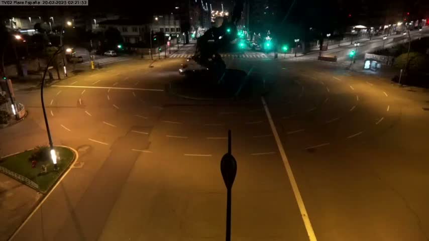 An empty roundabout and intersecting roads at night are illuminated by streetlights.