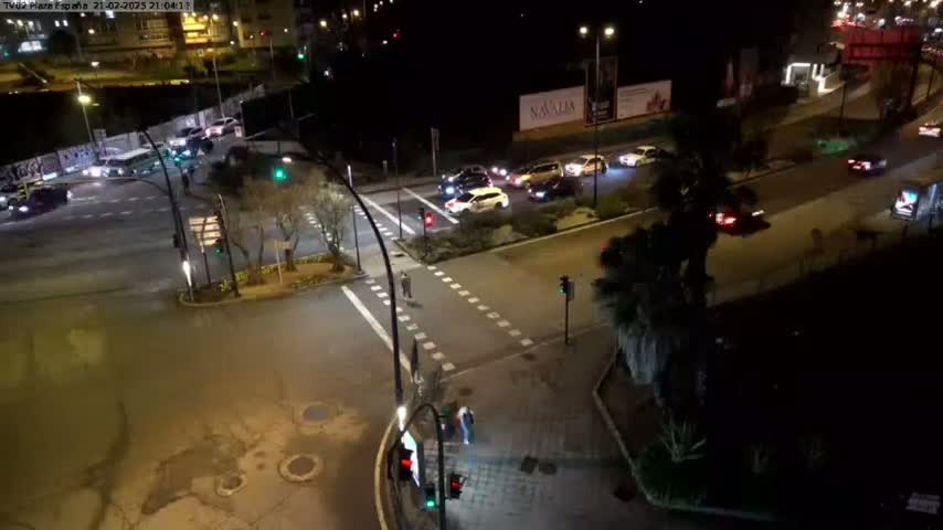 A nighttime overhead view of a city intersection with several cars at a crossroads under clear skies.