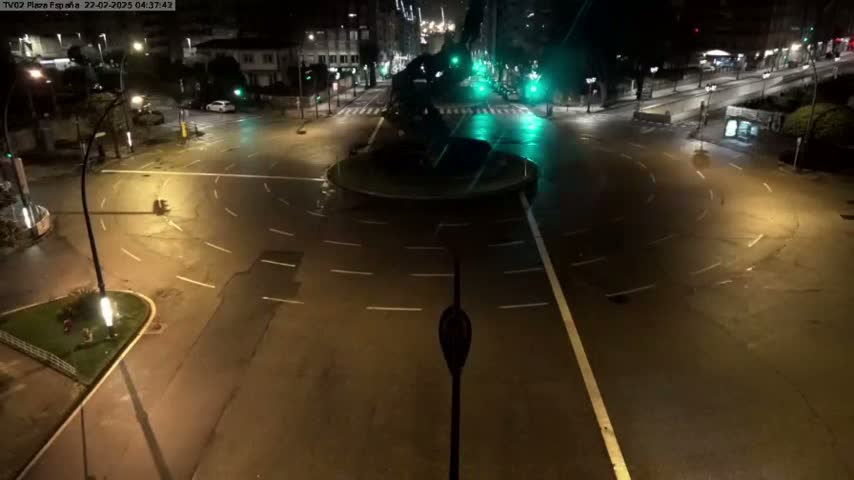 An empty roundabout and surrounding streets are illuminated at night by streetlights.