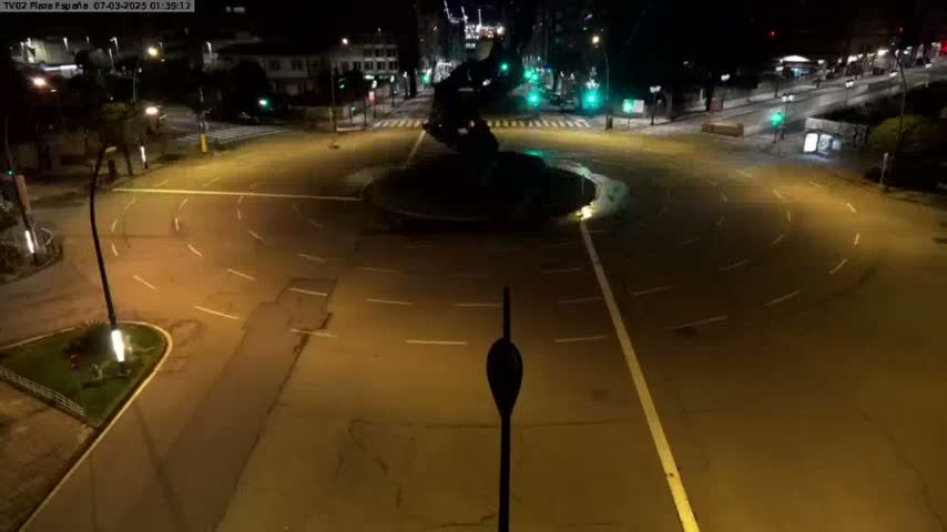 A mostly empty, circular roundabout at night, illuminated by streetlights.