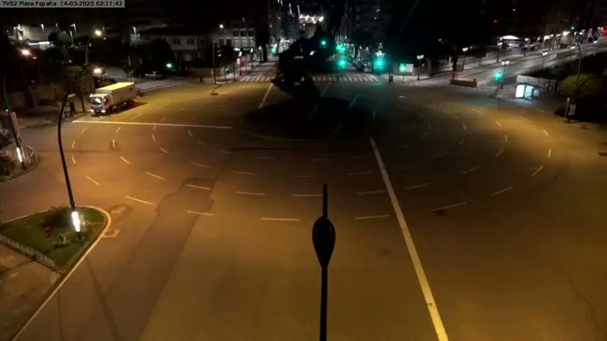 A nighttime overhead view of a mostly empty roundabout with a single truck, illuminated by streetlights.