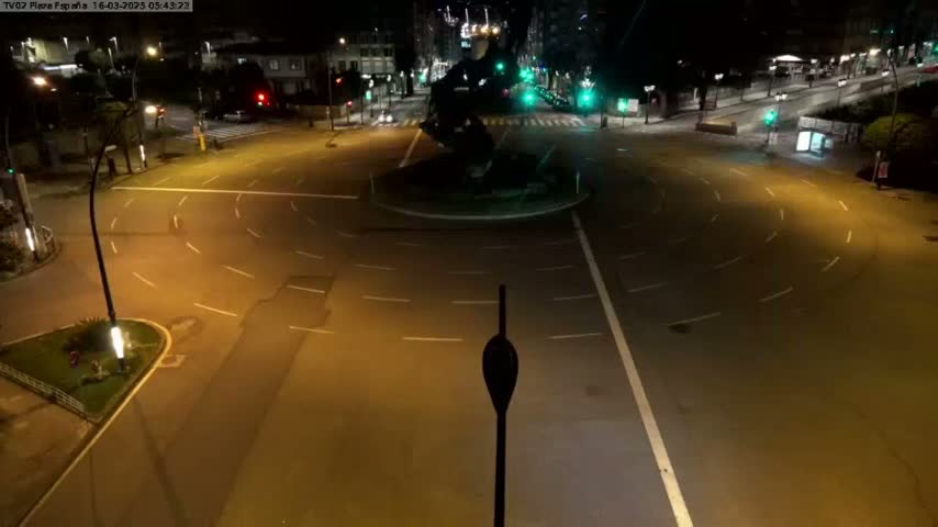 An empty roundabout and surrounding roads are illuminated at night.