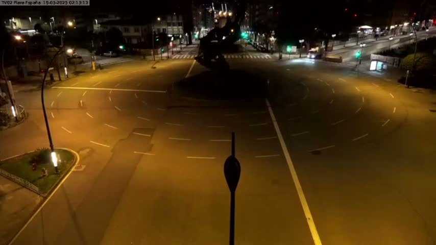 A mostly empty roundabout at night, illuminated by streetlights.