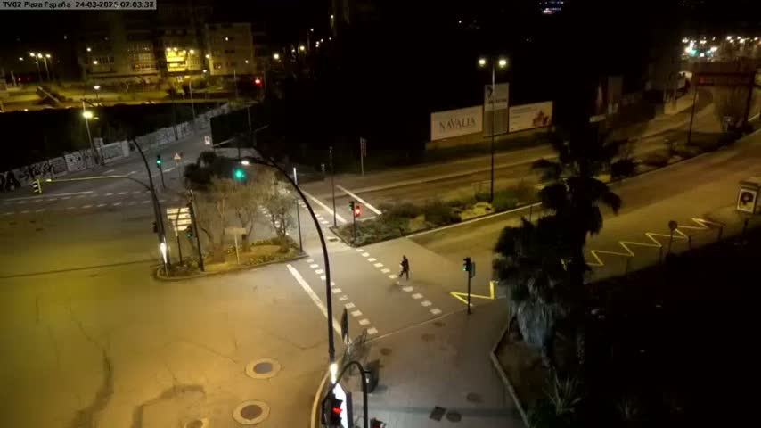 A nighttime aerial view of a mostly empty intersection with a pedestrian crossing, illuminated by streetlights.