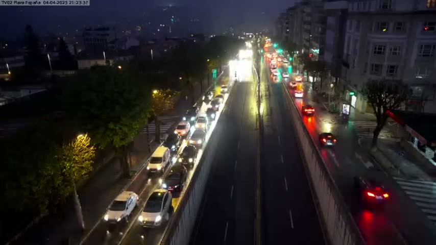 A rain-slicked city street at night is congested with slow-moving traffic in both directions.
