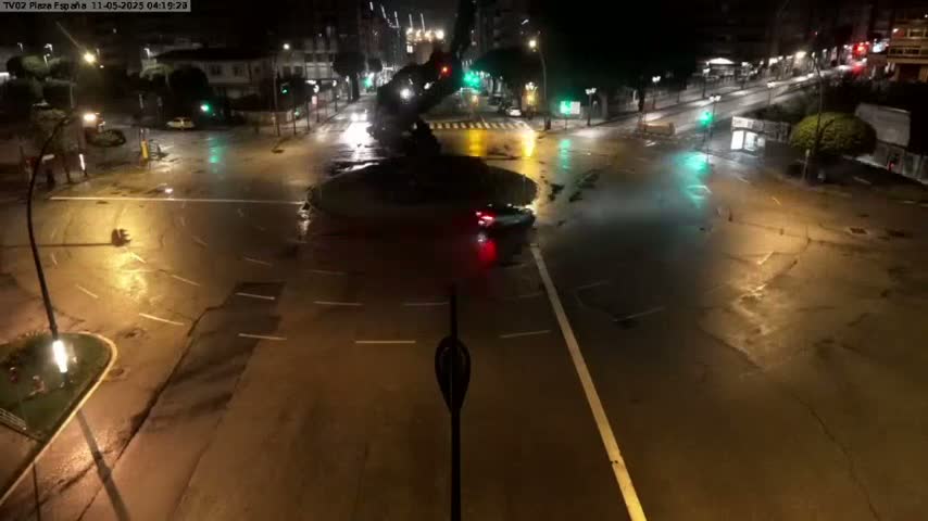 A nighttime aerial view of a flooded intersection with several cars and streetlights illuminating the waterlogged roads.