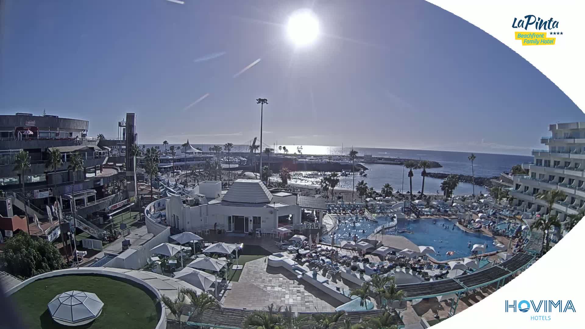A sunny day at a resort with a swimming pool and beach access overlooking a calm ocean.