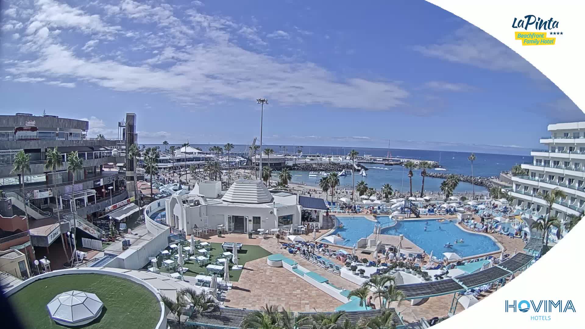 A resort with multiple pools and a beachfront location is shown on a partly cloudy day.