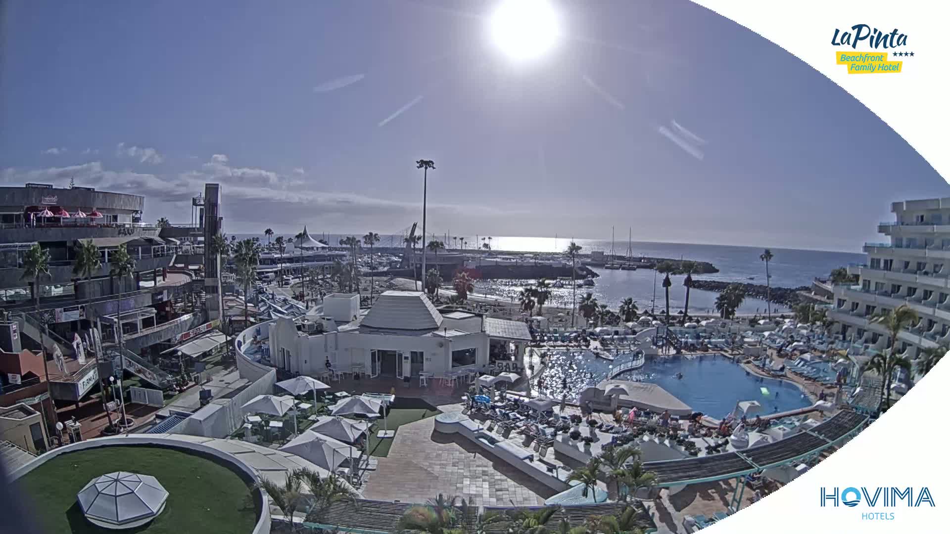 A sunny day overlooking a resort with a swimming pool, a marina, and the ocean.