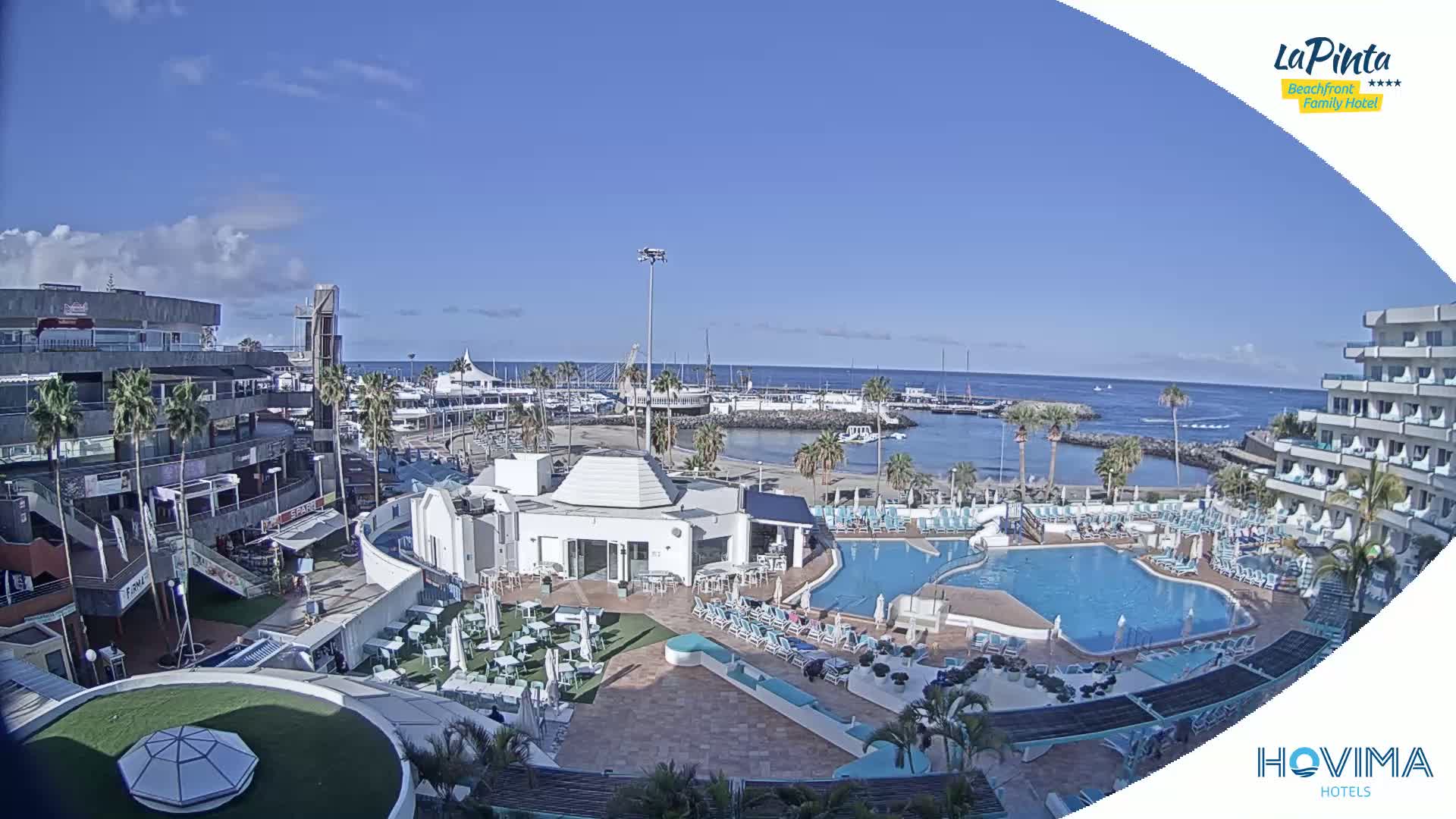 A sunny day overlooking a resort with a marina, pool, and surrounding buildings.