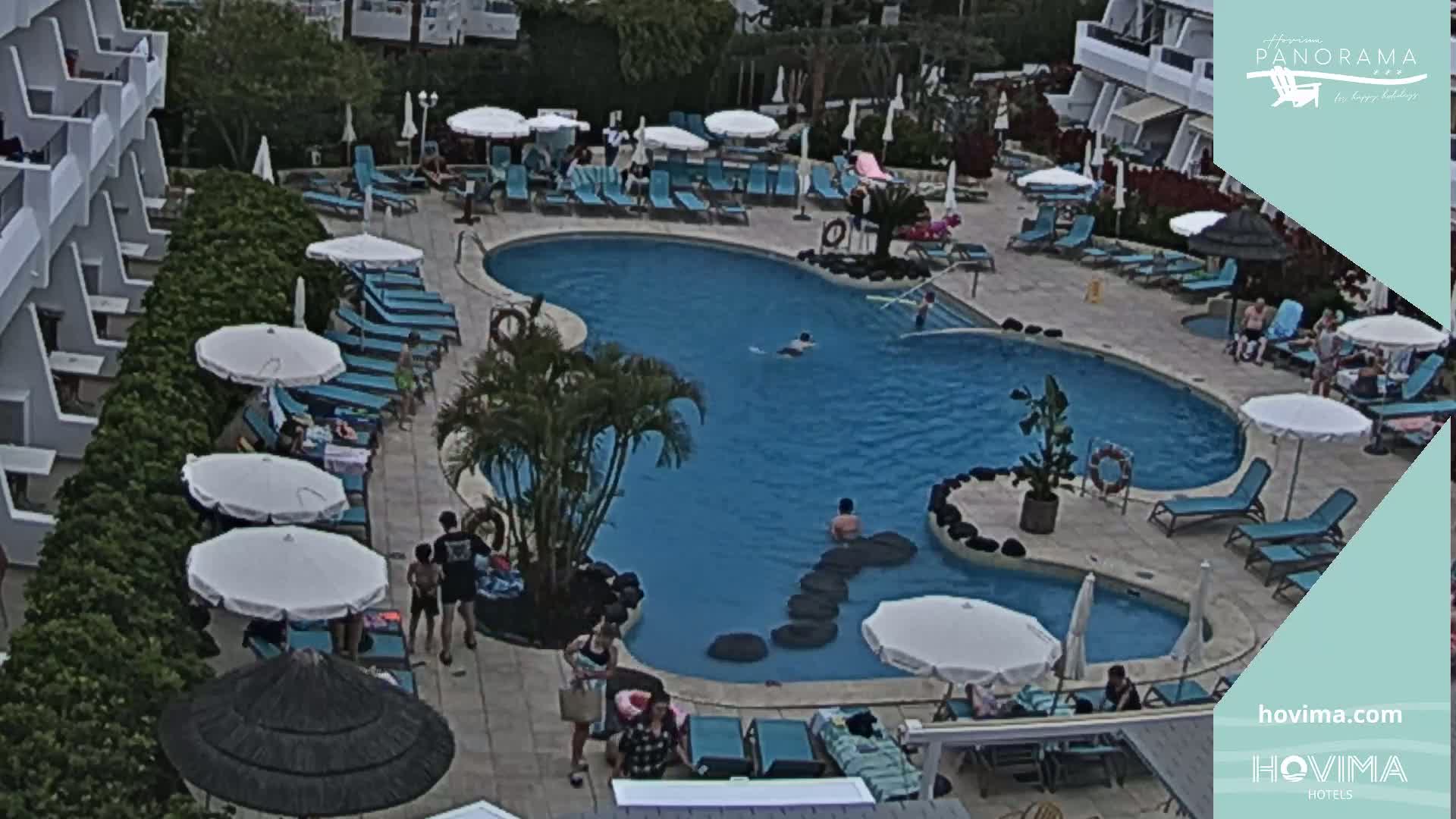 An overhead view shows a resort pool area with numerous lounge chairs and umbrellas surrounding a kidney-shaped pool, with several people swimming and relaxing around it.