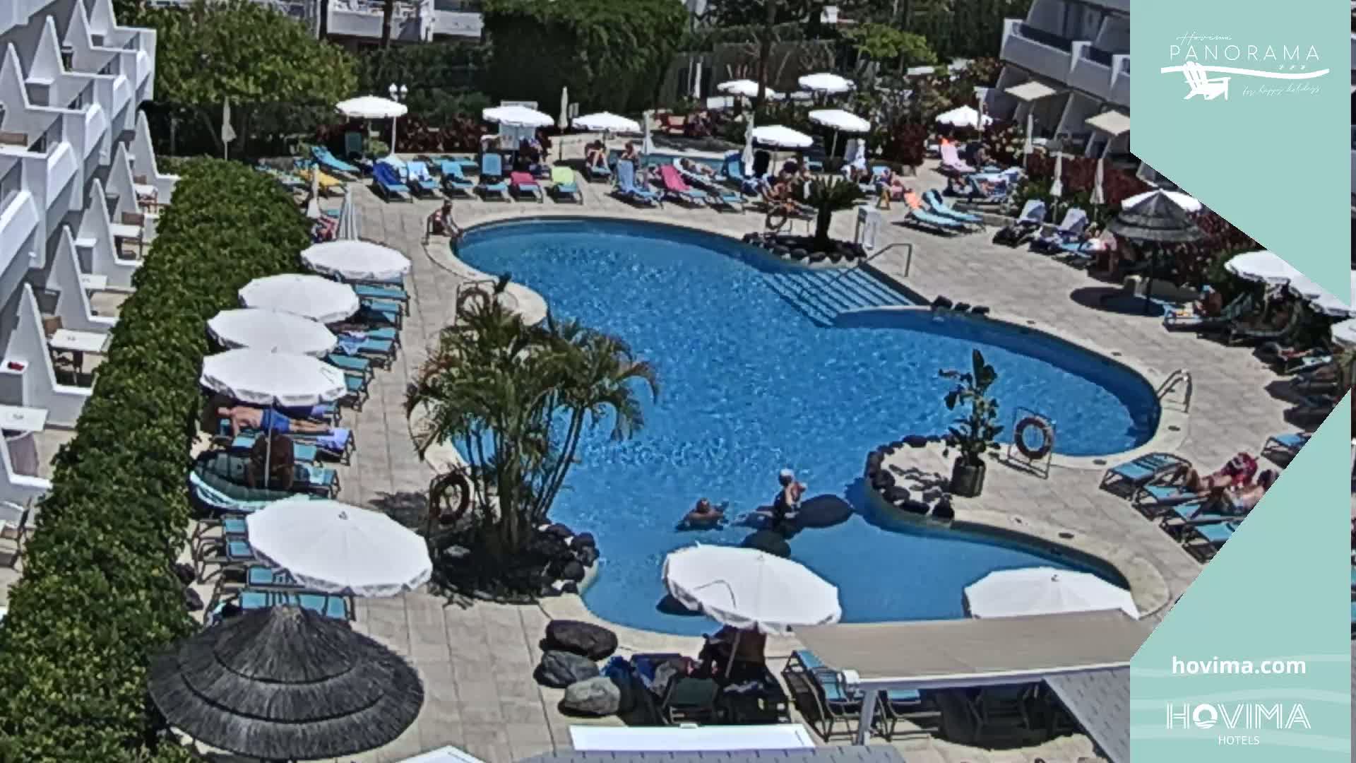 A resort pool with surrounding lounge chairs and umbrellas on a sunny day.