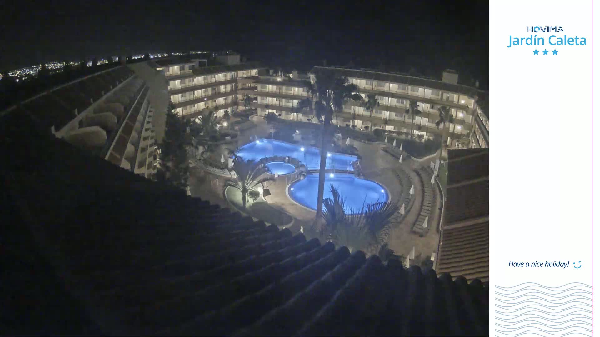 An illuminated resort pool and surrounding buildings are visible at night.