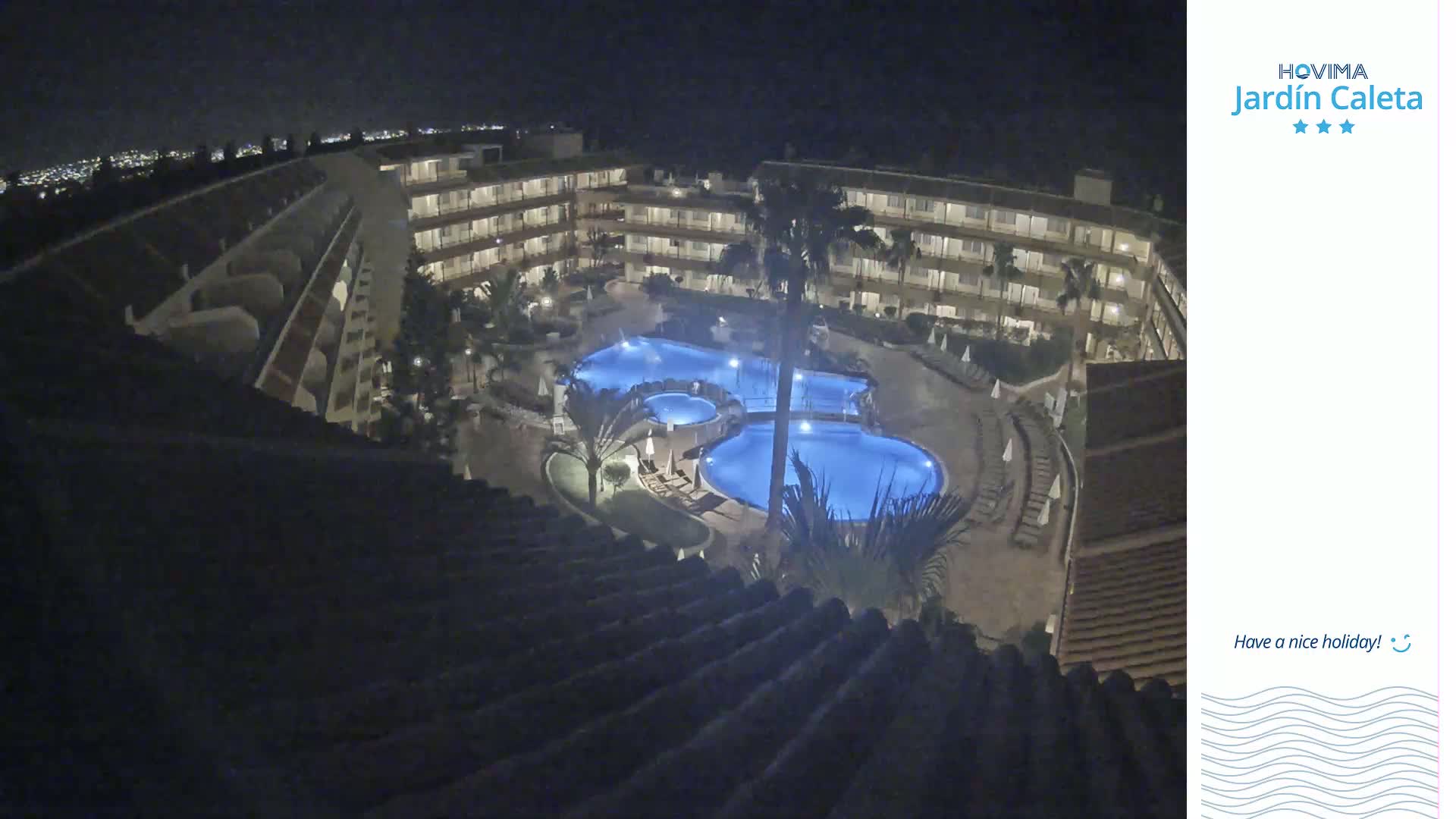 A nighttime overhead view shows a multi-story building complex surrounding a lit swimming pool area.