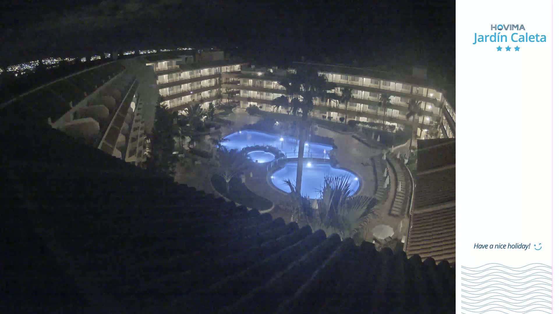 A nighttime view of a multi-story building complex surrounding a lit swimming pool area.
