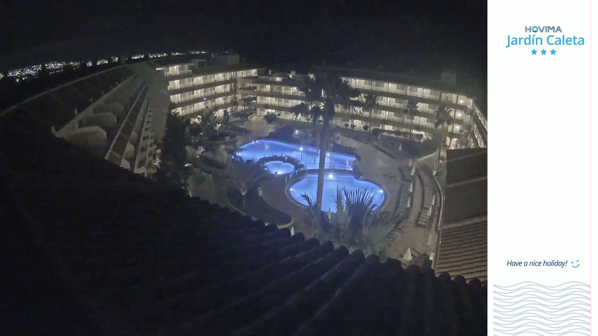 An illuminated multi-level hotel complex with a large, irregularly shaped pool at night.