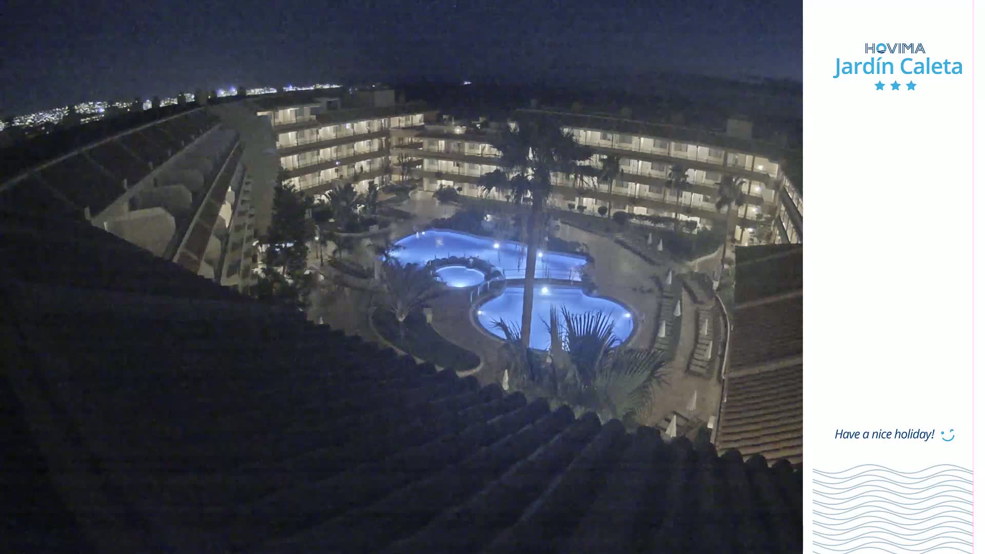 A nighttime view of a multi-story building complex with a lit swimming pool in the courtyard.