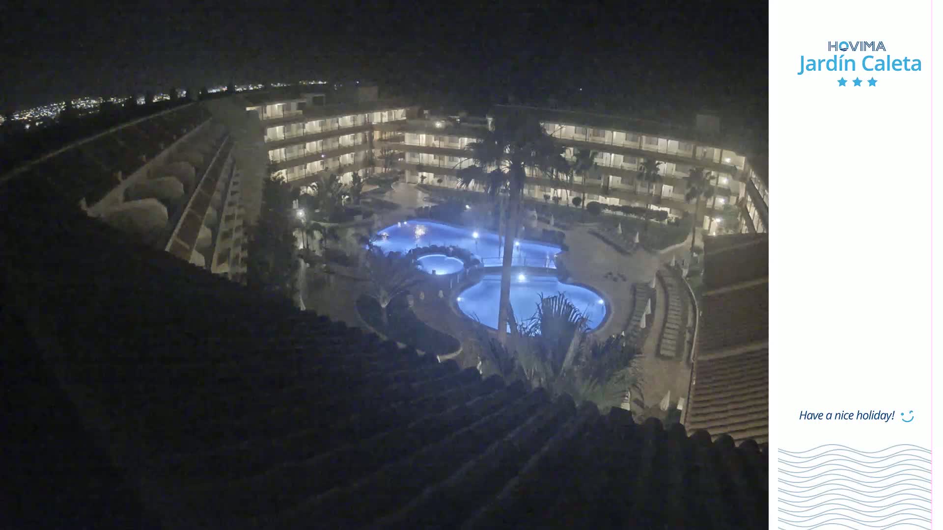 An illuminated multi-level hotel complex with a large, irregularly shaped pool at night.