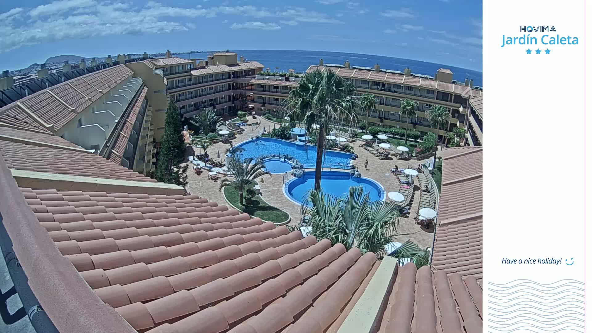 A sunny day overlooks a resort's courtyard with a swimming pool and surrounding buildings.