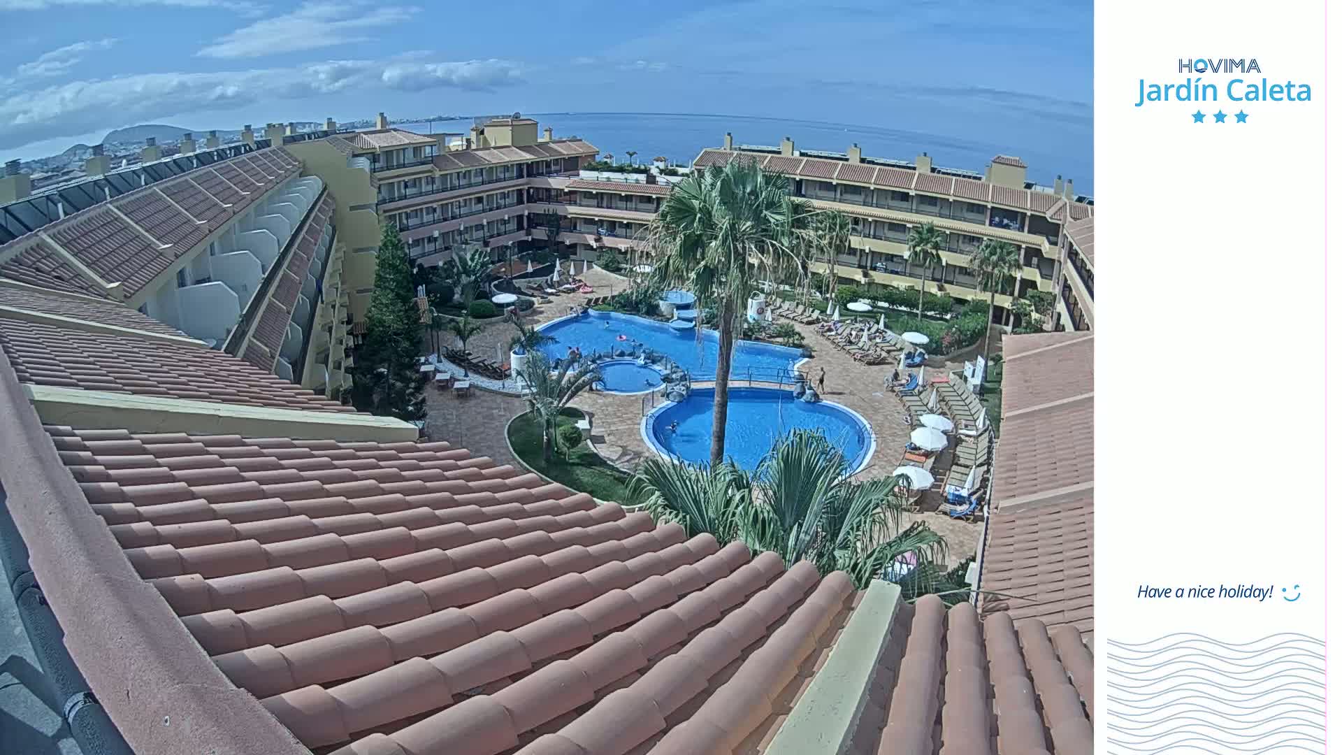 A sunny day overlooking a resort with multiple pools surrounded by buildings and palm trees.