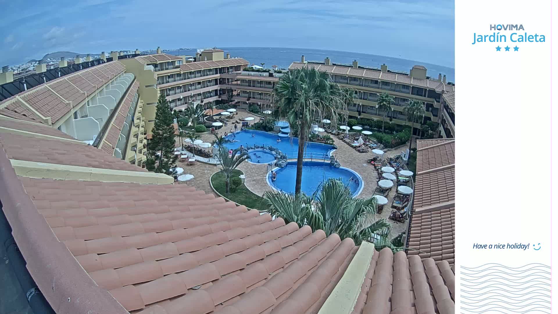 A sunny day overlooks a resort complex with multiple buildings surrounding a swimming pool area.