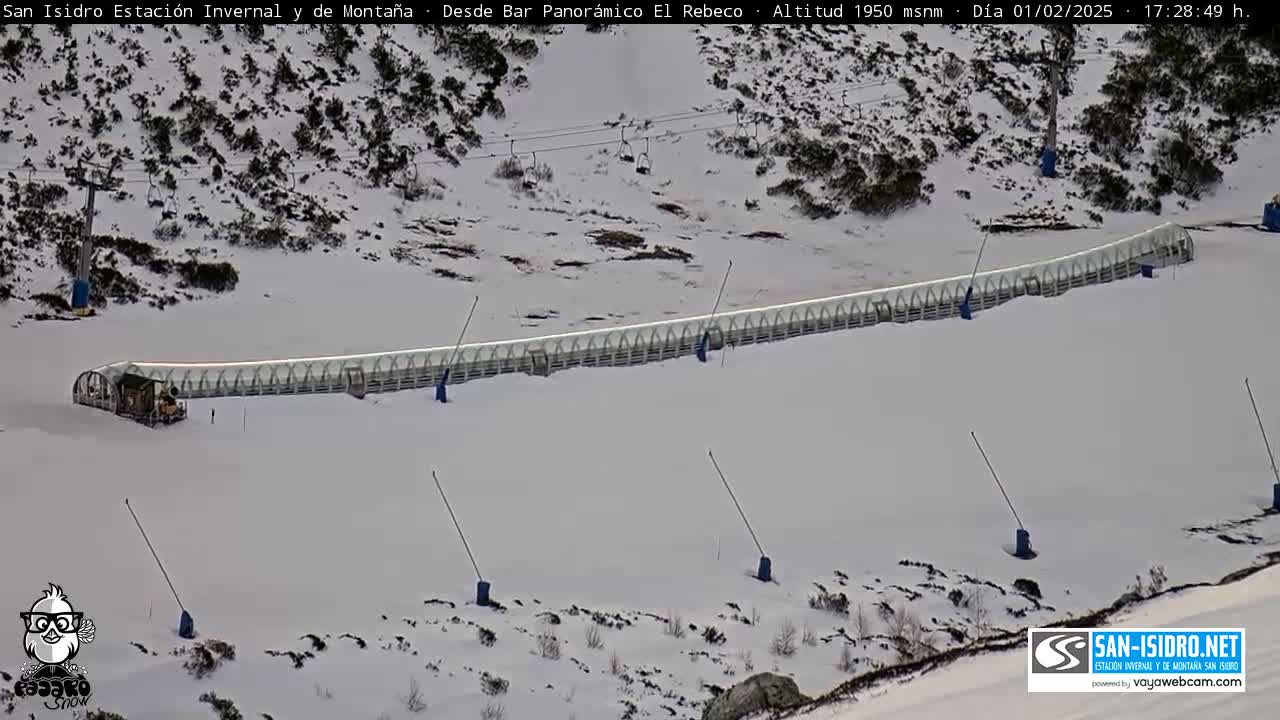 A long, covered ski lift sits on a snow-covered mountainside.