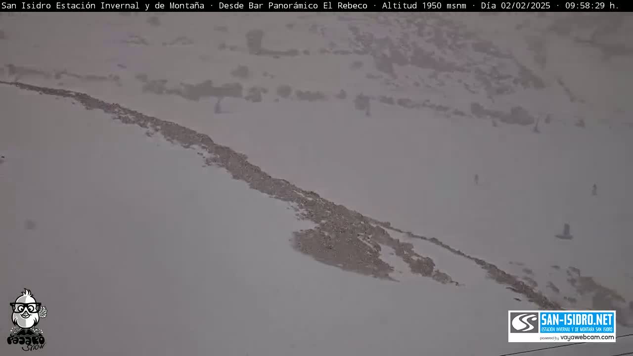 A snow-covered mountain slope with a few figures visible in the distance under overcast skies.