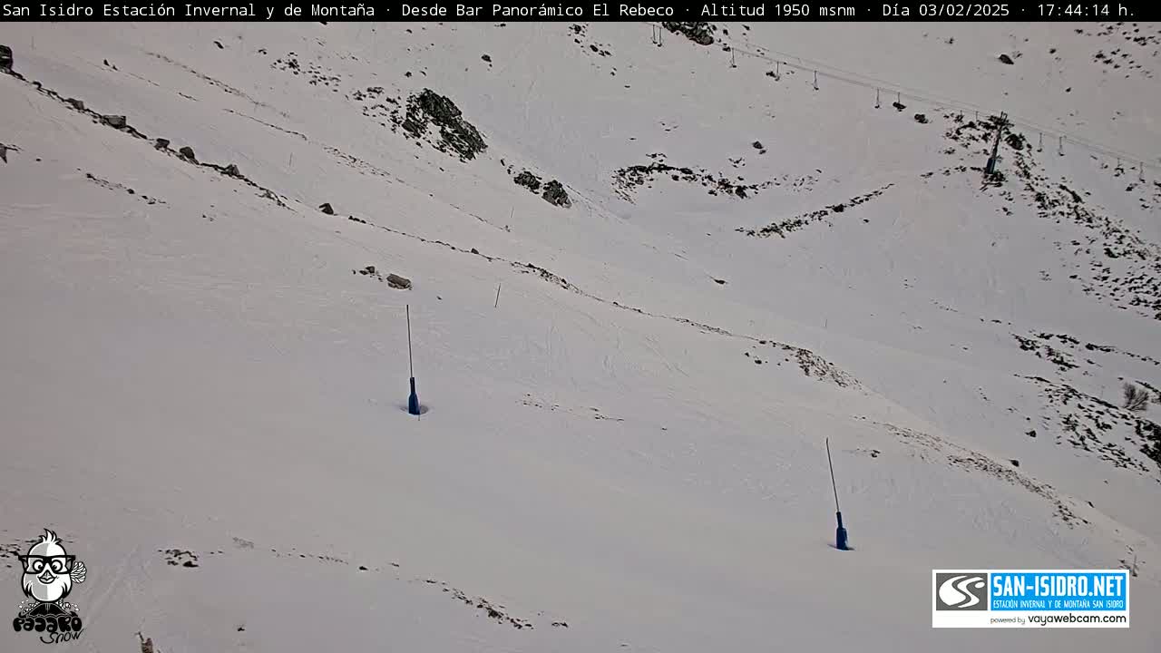 A snow-covered mountain slope with two tall, thin, dark poles sticking out of the snow.