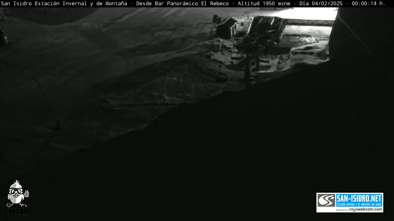 A nighttime, snow-covered mountain scene is visible from a high vantage point, showing a building and surrounding landscape under dark conditions.
