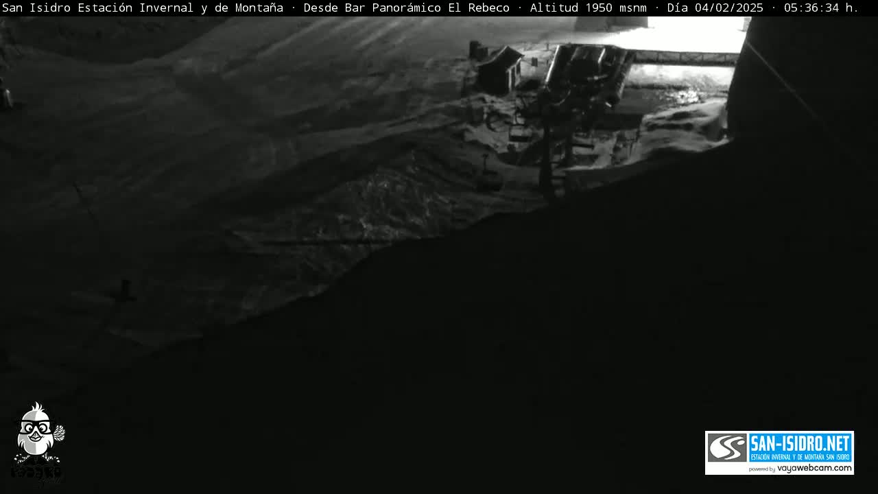 A nighttime, snow-covered mountain landscape is shown, with a building and what appears to be a ski lift visible in the distance.