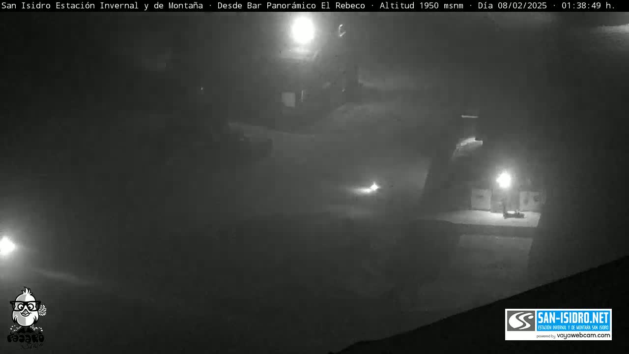 A nighttime, foggy scene shows dimly lit structures and a roadway.