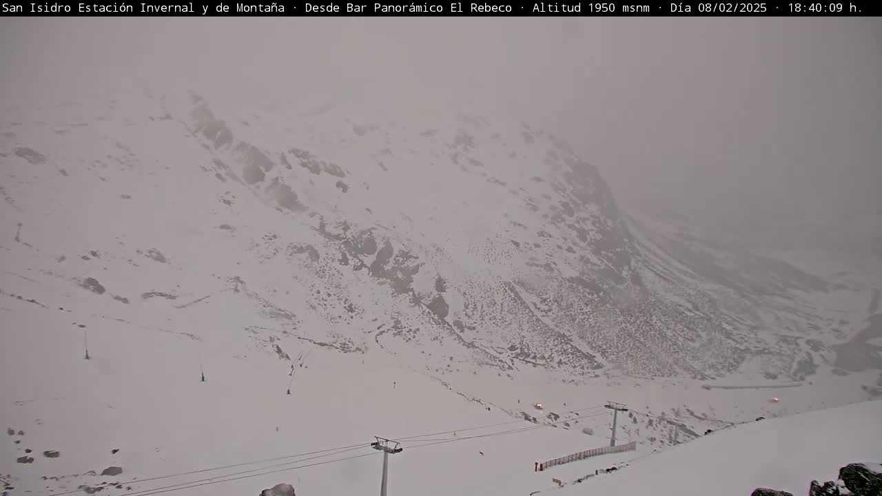 A snow-covered mountain slope with a ski lift is visible in foggy conditions.