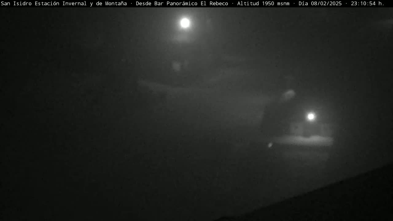 A nighttime, hazy, outdoor scene illuminated by a bright light source and a fainter light in the distance.