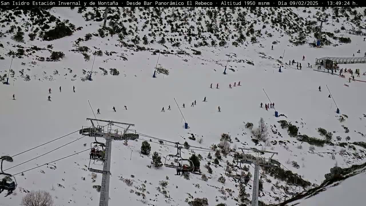A snowy ski slope with several skiers and chairlifts.