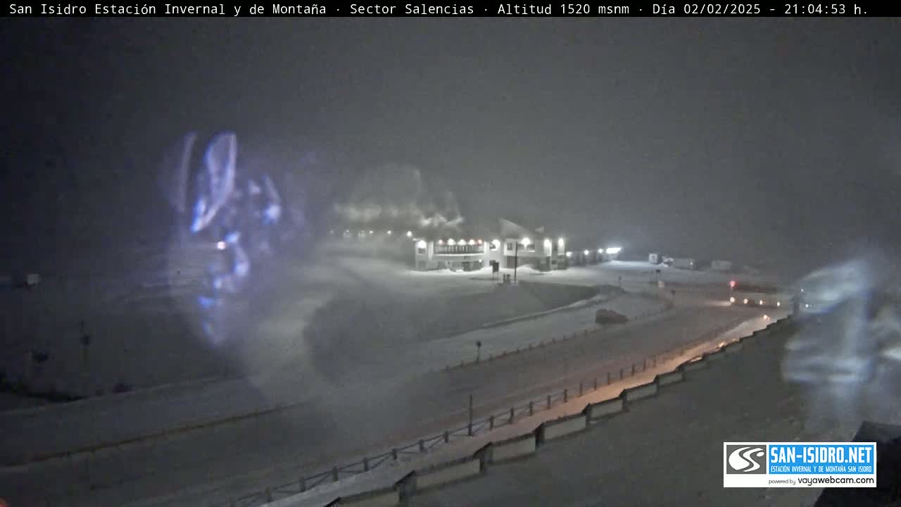A snow-covered landscape at night, with a building partially obscured by heavy snowfall.