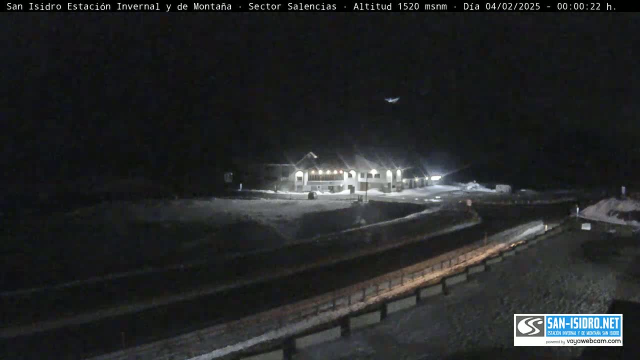 A snow-covered building complex is visible at night, under a dark sky.