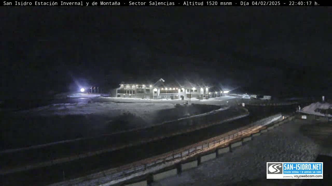A snow-covered building complex is illuminated at night, under a dark sky.
