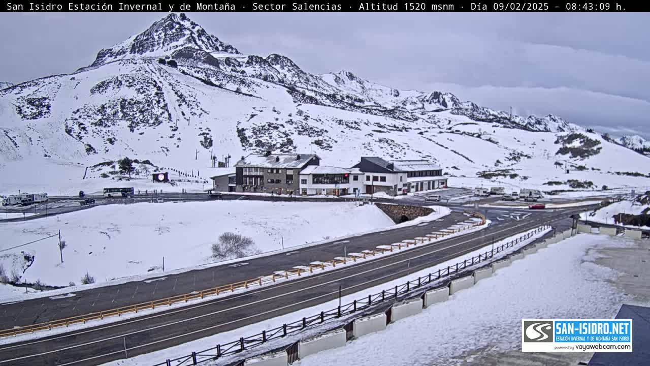 A snow-covered mountain landscape with a building complex and a road, under an overcast sky.