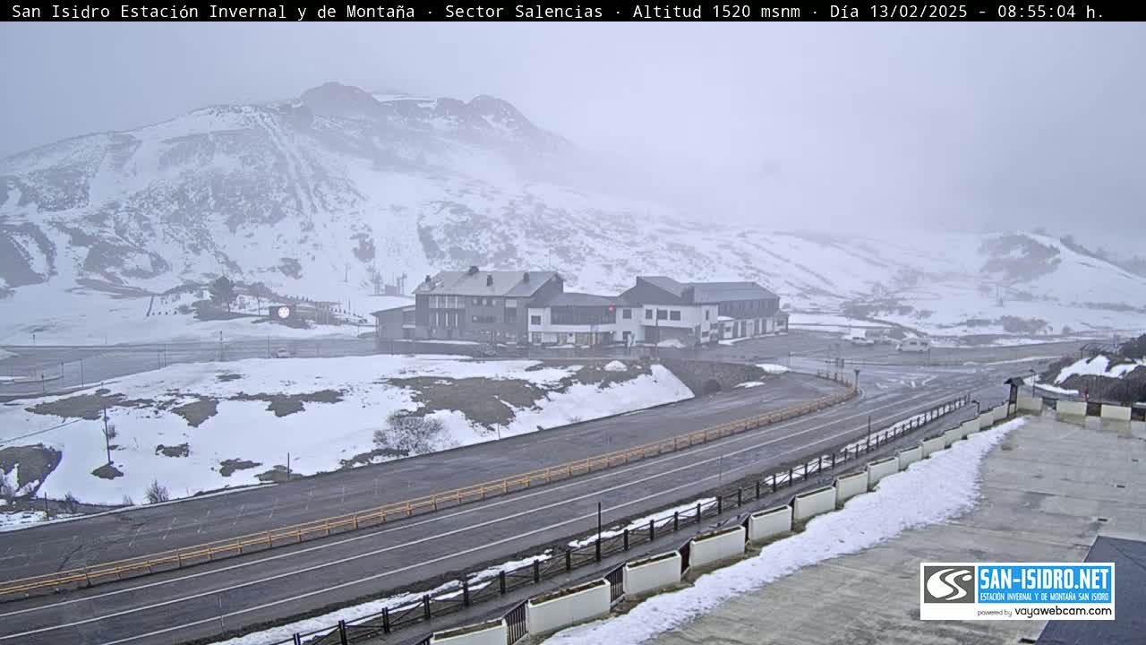 A snow-covered mountain landscape with a road and buildings is visible under hazy conditions.