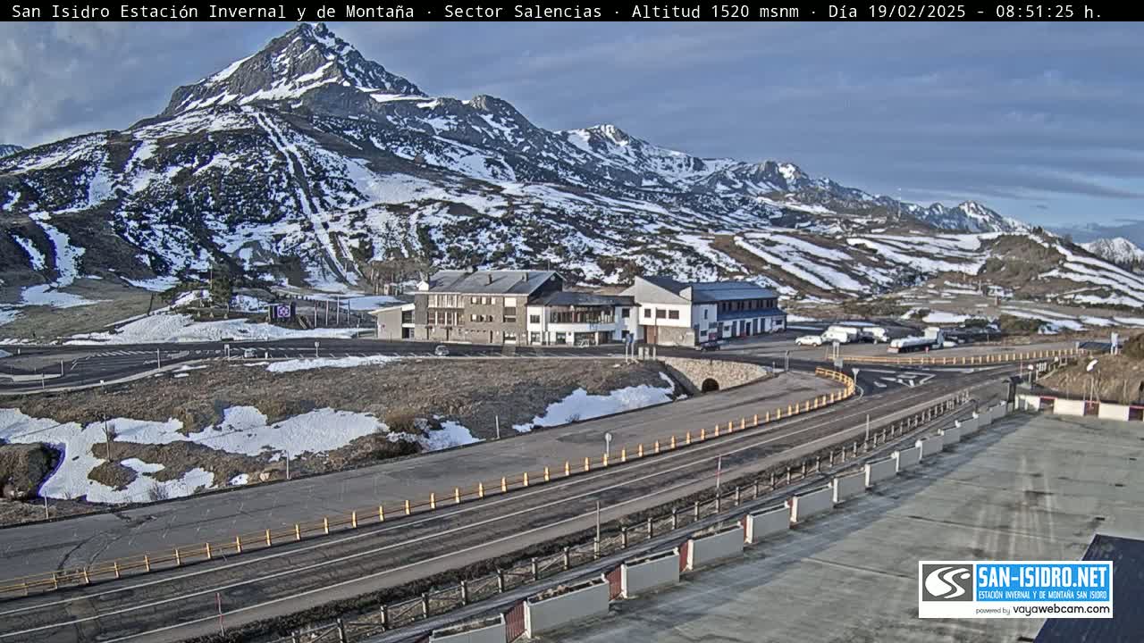 A mountain resort with snow-dusted slopes and a parking lot is visible under a mostly clear sky.