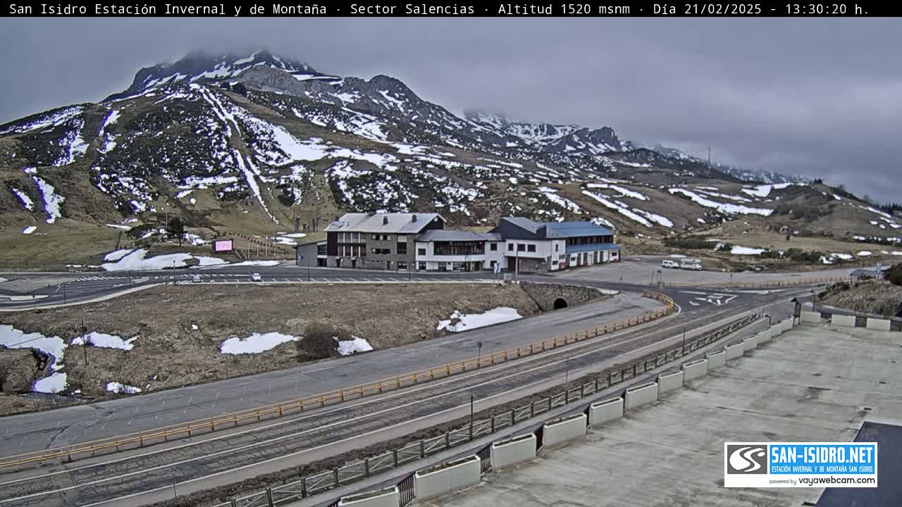 A mountain resort with snow-dusted hills and buildings under an overcast sky.