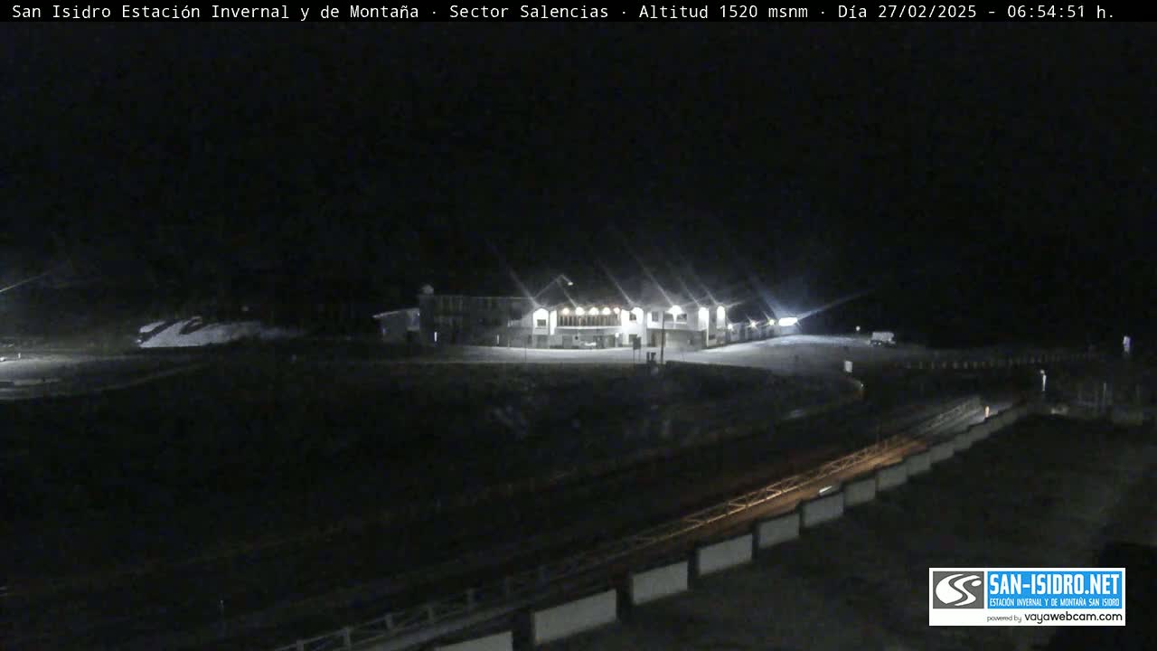 A brightly lit building sits on a snow-covered area at night.