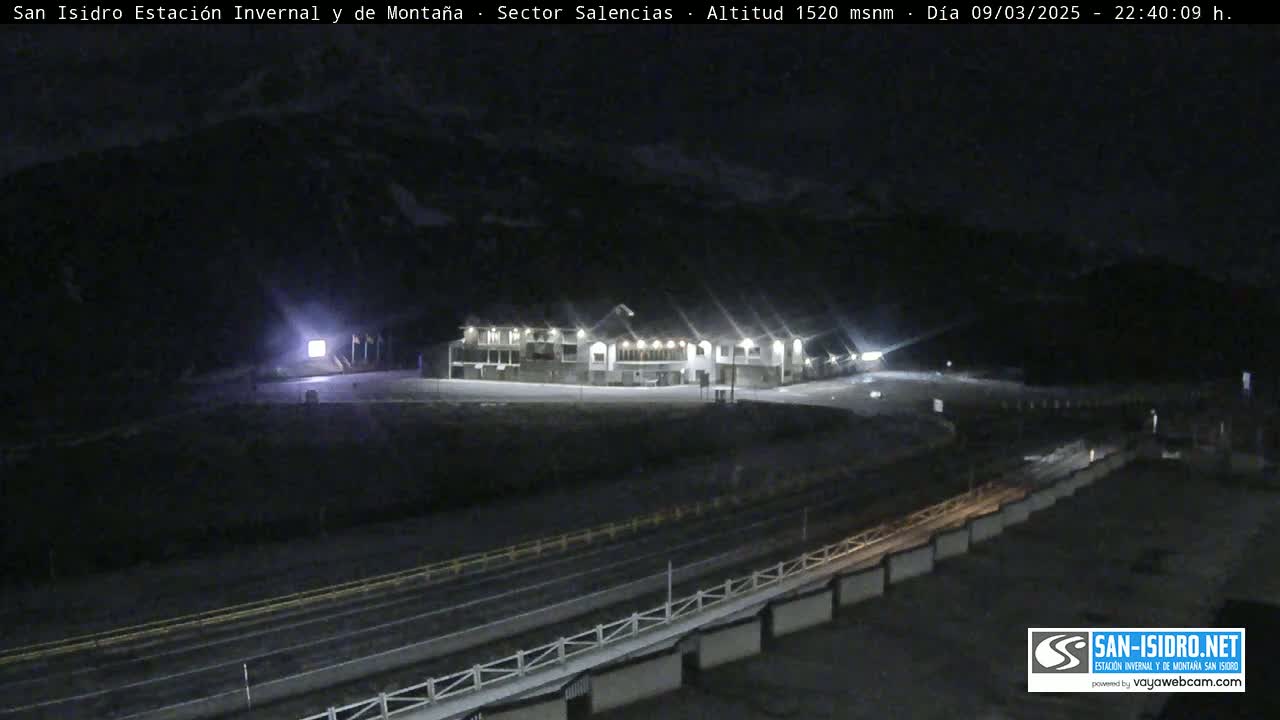 A brightly lit building sits in a snow-covered landscape at night.