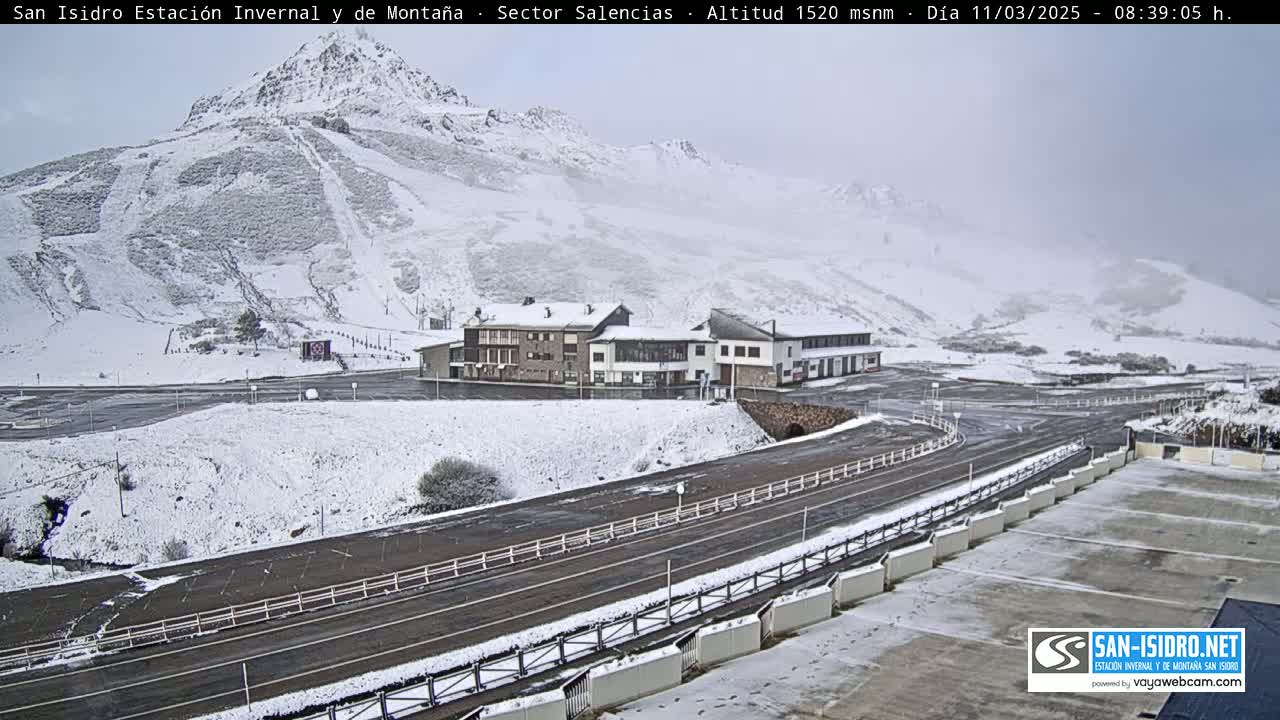 A snow-covered mountain landscape with a building complex and roads is visible under an overcast sky.