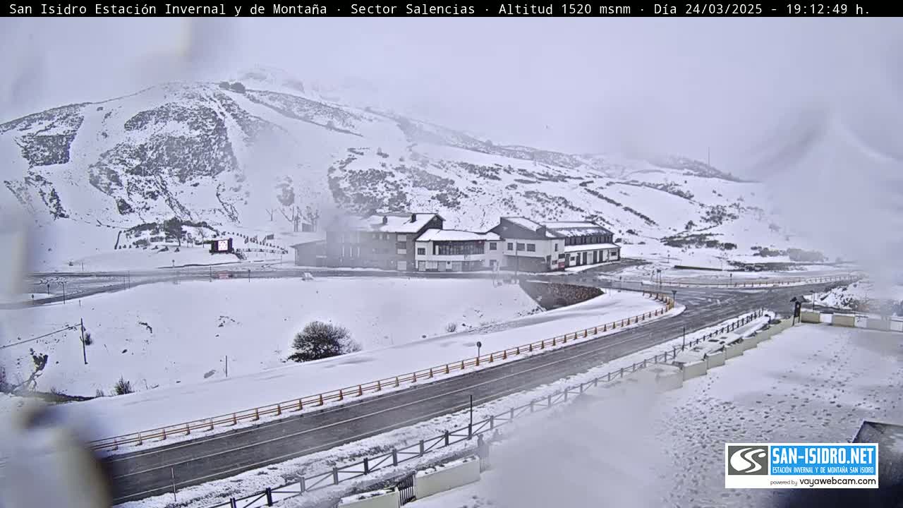 A snow-covered mountain landscape with a road and buildings is visible in overcast conditions.