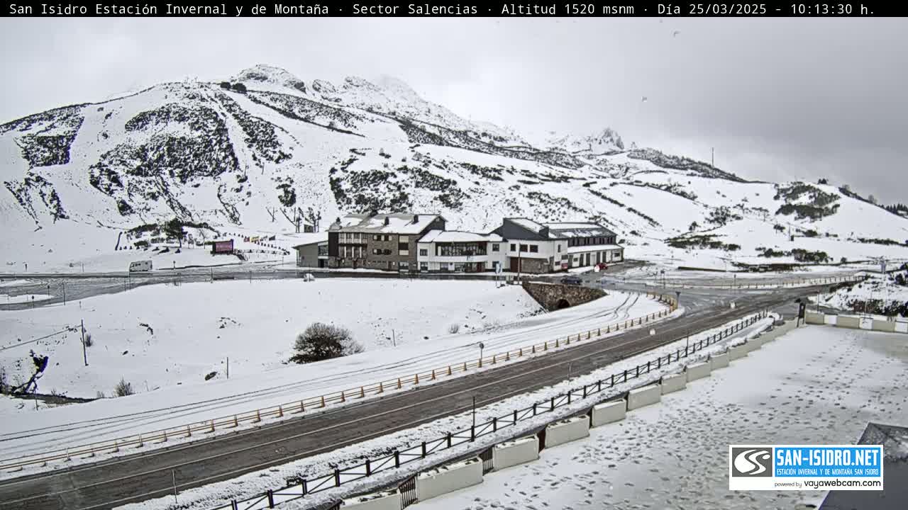 A snow-covered mountain resort town with a road and buildings, under an overcast sky.