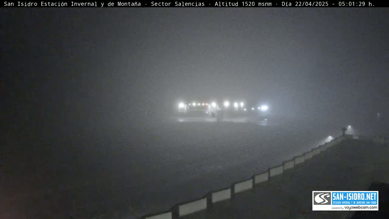 A foggy, dimly lit outdoor scene shows a roadway with low-lying structures and lights visible through the fog.