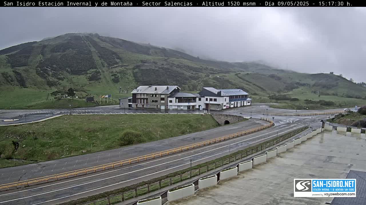 A mountainside ski resort with several buildings is visible on an overcast day.