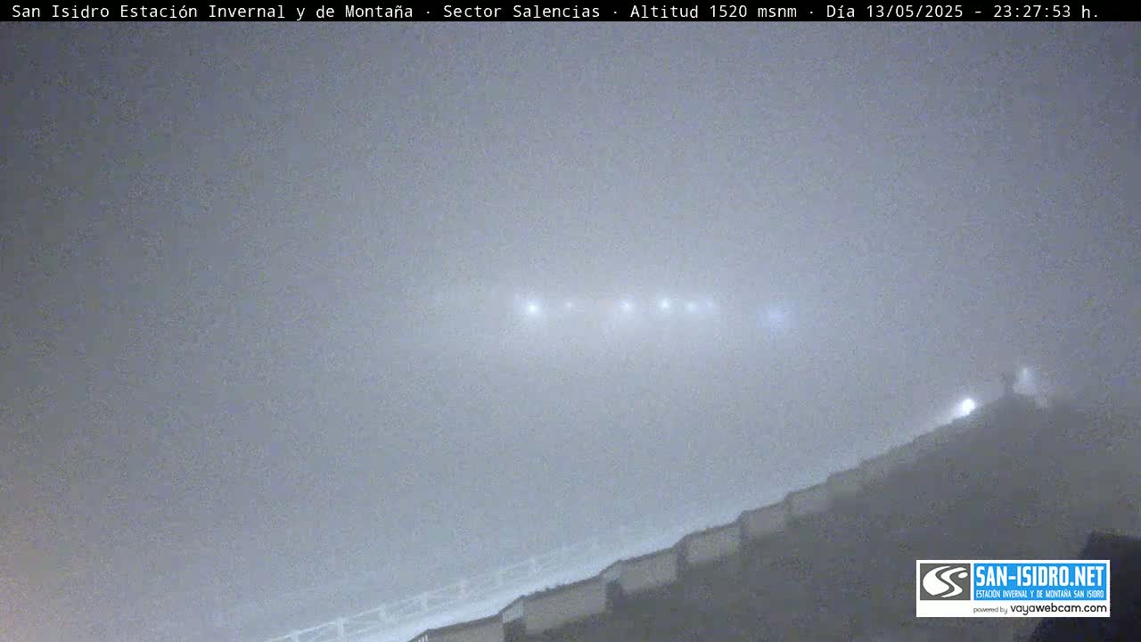 A foggy night scene shows a row of lights atop a hill.